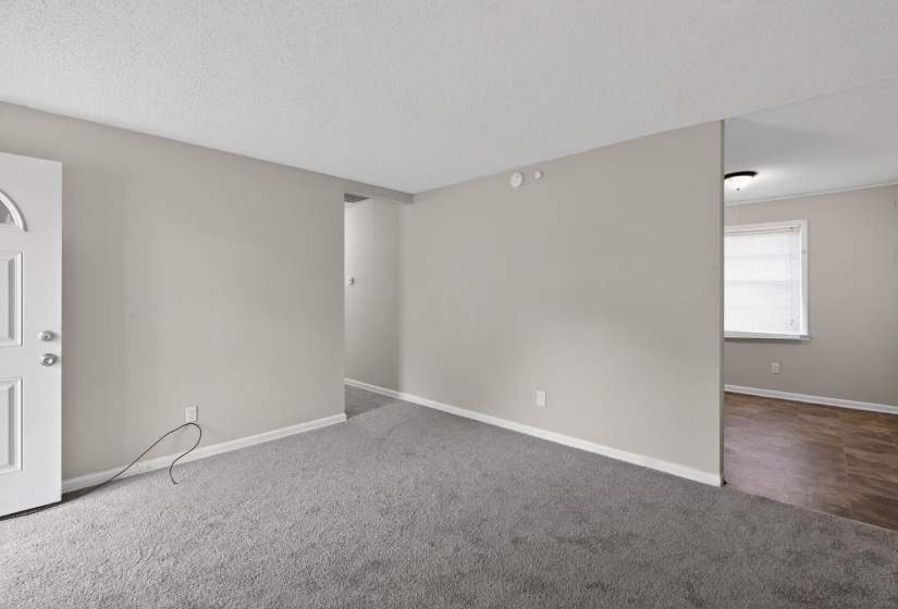 Carpeted spare room with a textured ceiling and baseboards