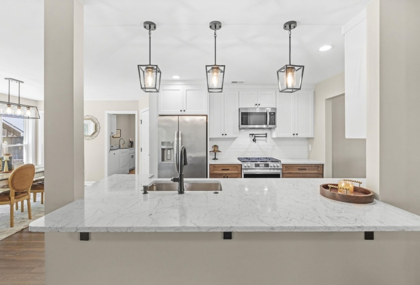 Kitchen with white cabinets, light stone countertops, stainless steel appliances, pendant lighting, and decorative backsplash