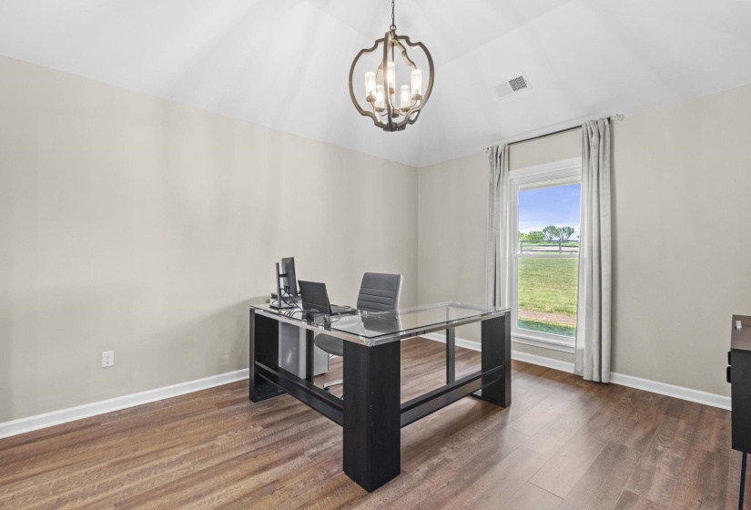 Office space featuring dark wood-style flooring, hanging lights, and vaulted ceiling
