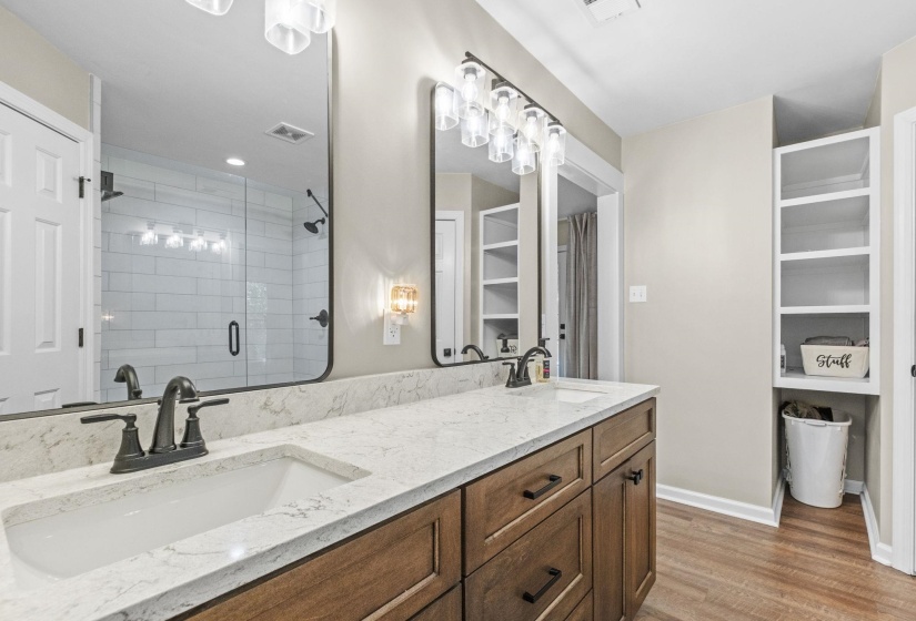 Full bathroom with double vanity, a shower stall, light wood-style floors, and a walk in closet