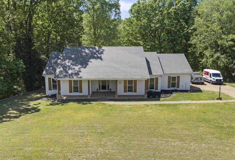 View of front of house featuring a shingled roof, covered porch, and a front yard