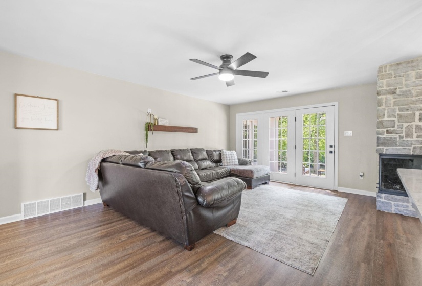 Living area featuring a stone fireplace, ceiling fan, and wood finished floors