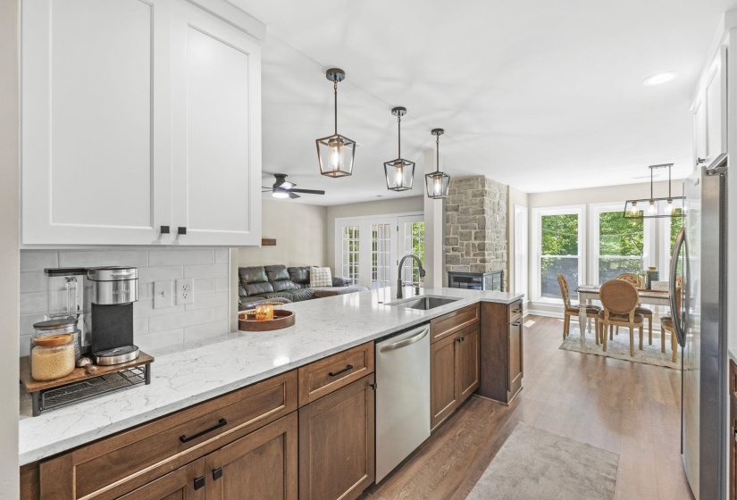 Kitchen with open floor plan, a ceiling fan, dark wood finished floors, light stone counters, and stainless steel appliances