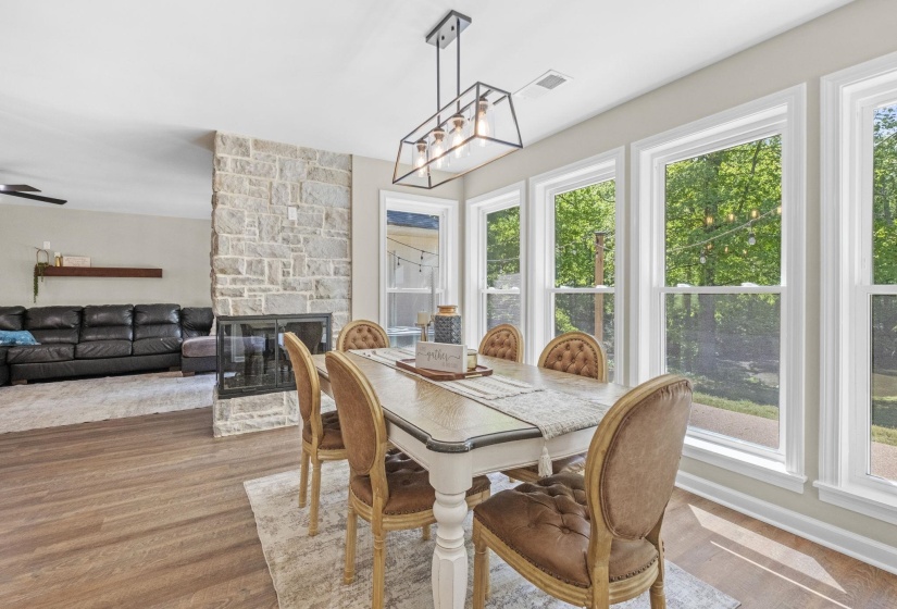Dining space featuring a stone fireplace, wood finished floors, and a chandelier