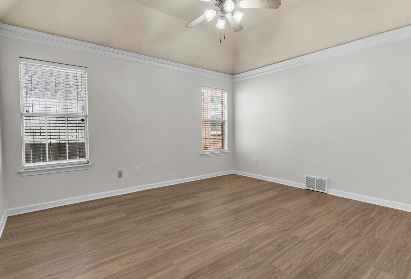 Empty room with ceiling fan, dark wood finished floors, ornamental molding, and lofted ceiling