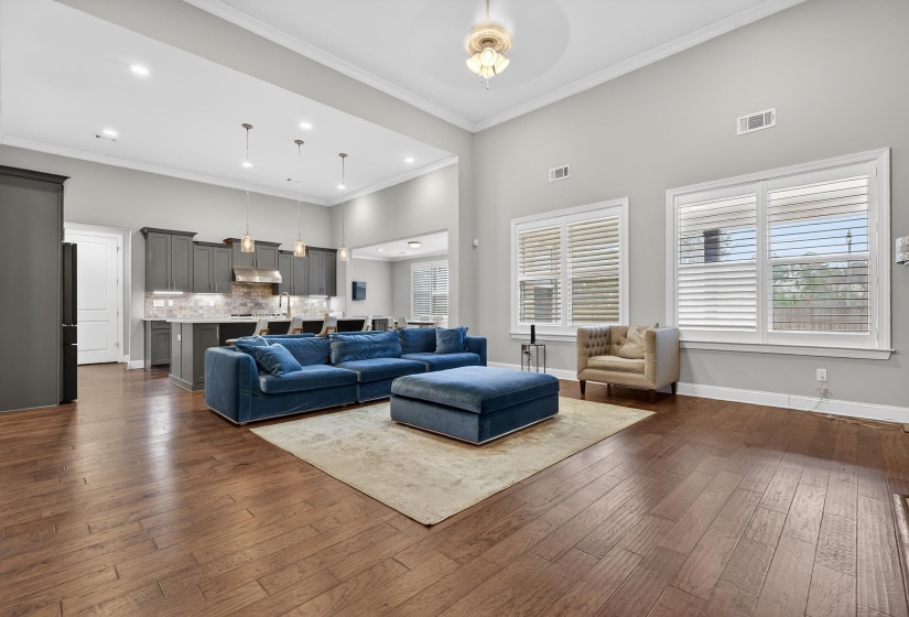 Living area featuring a high ceiling, ornamental molding, dark wood-style floors, and a ceiling fan