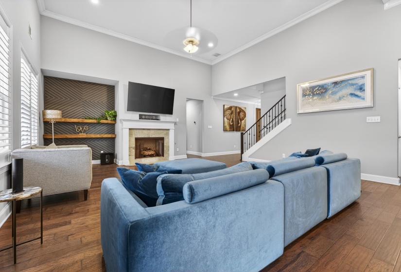 Living area with ornamental molding, a tiled fireplace, hardwood / wood-style flooring, a high ceiling, and recessed lighting