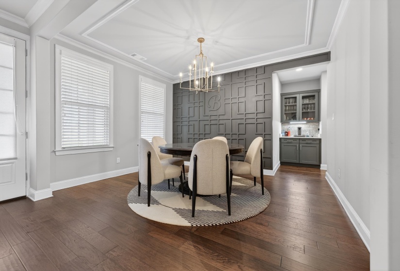 Dining room featuring dark wood-style floors, ornamental molding, and hanging lights