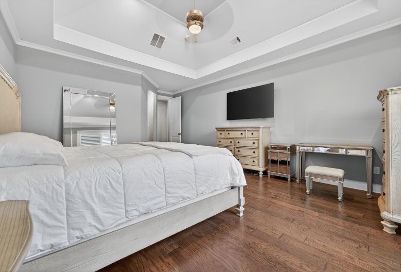 Bedroom featuring crown molding, a tray ceiling, dark wood finished floors, and a ceiling fan