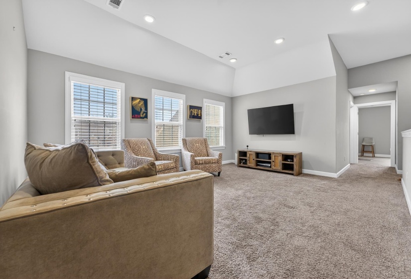 Living area featuring light colored carpet, vaulted ceiling, and recessed lighting