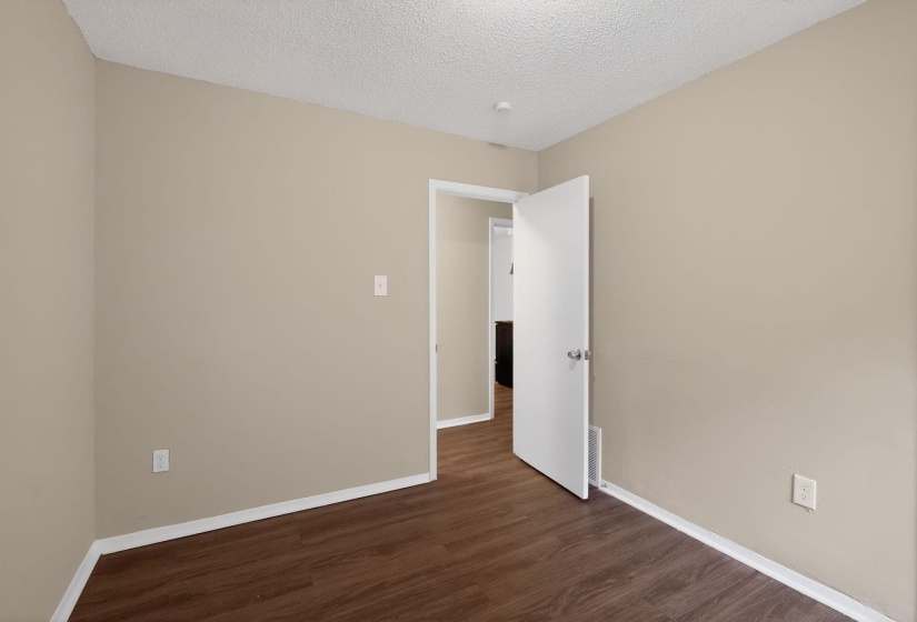 Unfurnished room featuring dark wood-type flooring and a textured ceiling