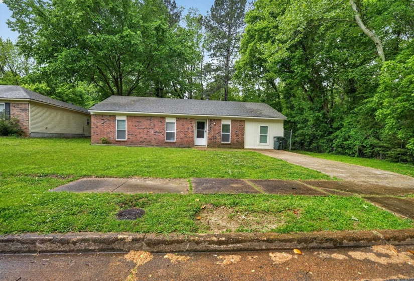Ranch-style home featuring a front yard, brick siding, and concrete driveway