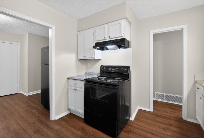 Kitchen with black appliances, a textured ceiling, white cabinetry, light countertops, and dark wood-style floors