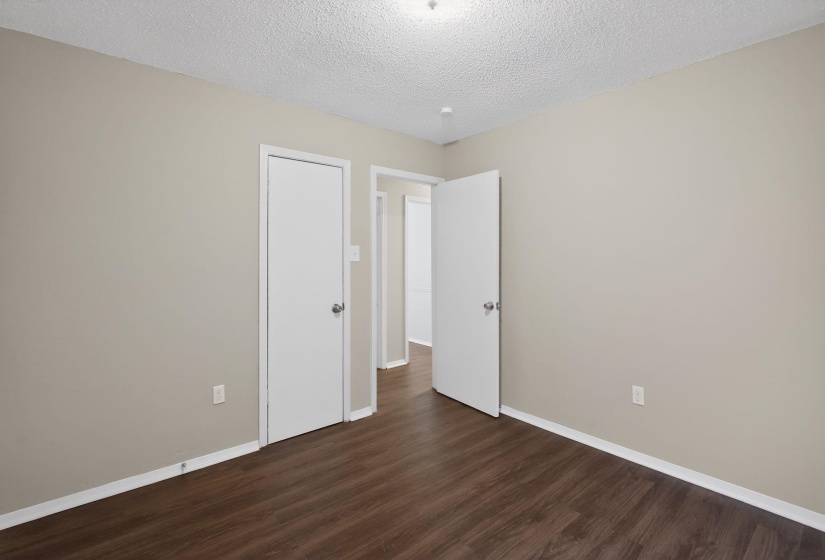 Unfurnished bedroom featuring a textured ceiling and dark wood finished floors