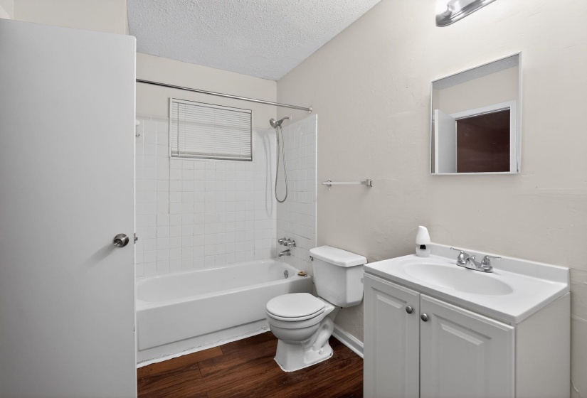Full bath with vanity, a textured ceiling, dark wood-style floors, and shower / washtub combination