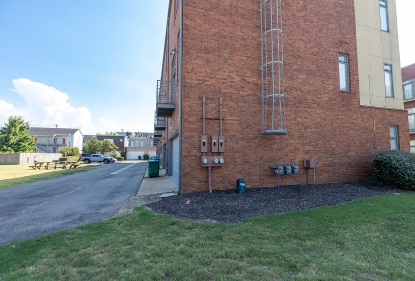 View of side of property with driveway, brick siding, a garage, and a sitting area
