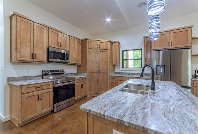 Kitchen with stainless steel appliances, light stone countertops, concrete flooring, vaulted ceiling, and recessed lighting