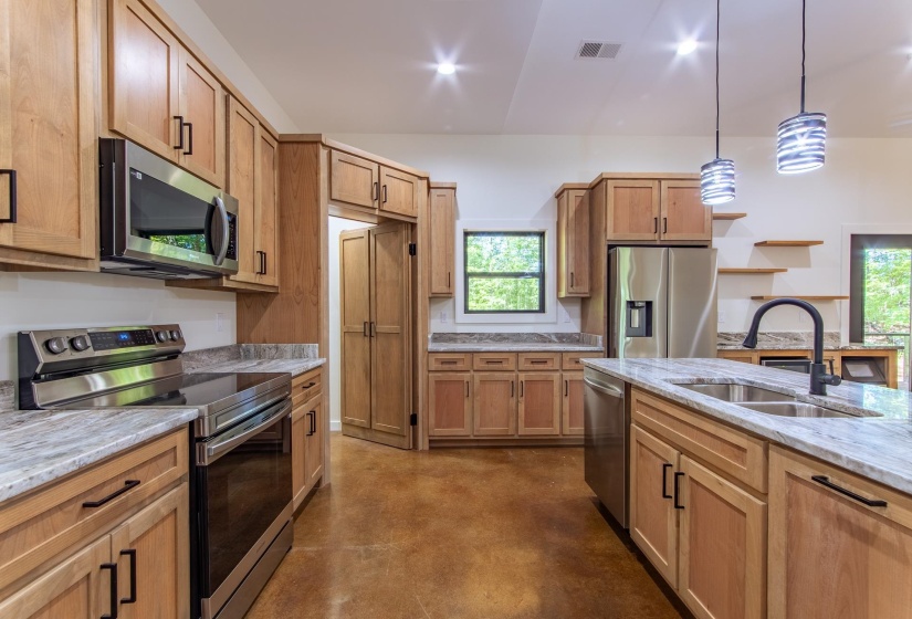 Kitchen featuring stainless steel appliances, concrete floors, light stone countertops, pendant lighting, and open shelves