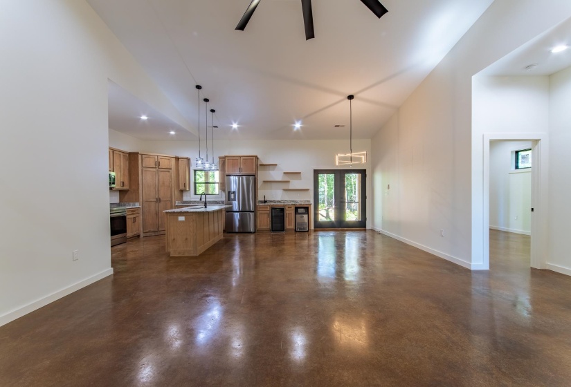 Unfurnished living room with concrete floors, french doors, ceiling fan, a high ceiling, and recessed lighting