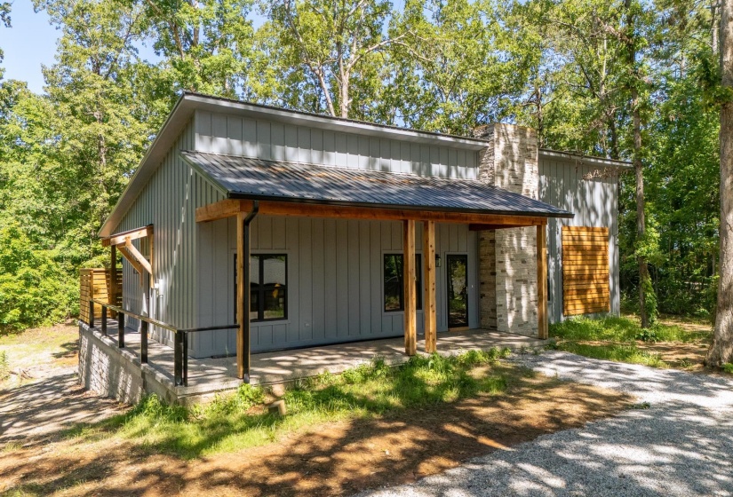 View of front of home with a metal roof, a porch, board and batten siding, and a chimney