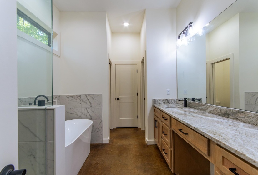 Full bath featuring vanity, a soaking tub, concrete floors, and recessed lighting