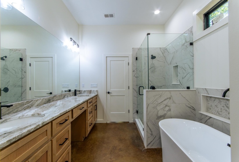 Full bath featuring double vanity, a marble finish shower, a freestanding bath, and finished concrete floors