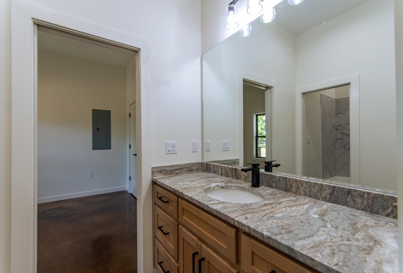 Full bath featuring vanity, electric panel, and finished concrete flooring
