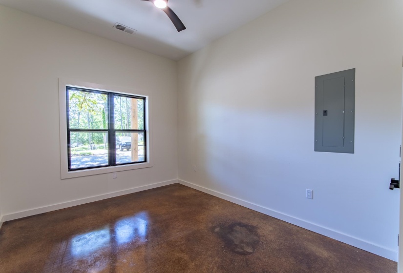 Unfurnished room featuring electric panel, concrete floors, and ceiling fan