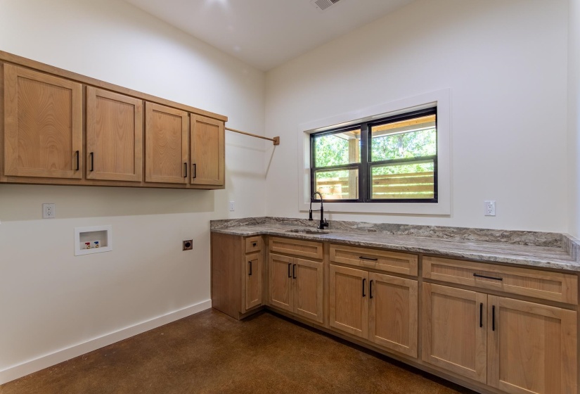 Laundry area with finished concrete flooring, cabinet space, washer hookup, and hookup for an electric dryer