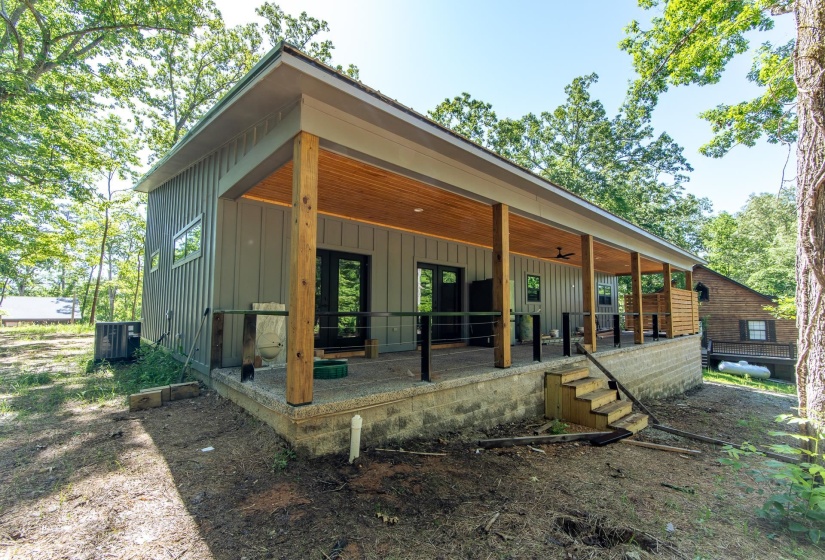 Rear view of house featuring board and batten siding, covered porch, and a ceiling fan