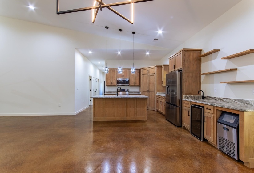 Kitchen with finished concrete floors, lofted ceiling, open shelves, wine cooler, and stainless steel appliances