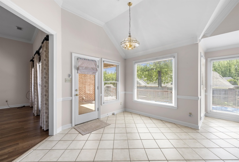 Breakfast area with lofted ceiling, crown molding, hanging lights, light tile patterned floors, and plenty of natural light