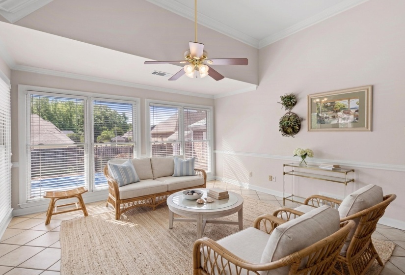 Hearth Room featuring light tile patterned floors, crown molding, lofted ceiling, and a ceiling fan