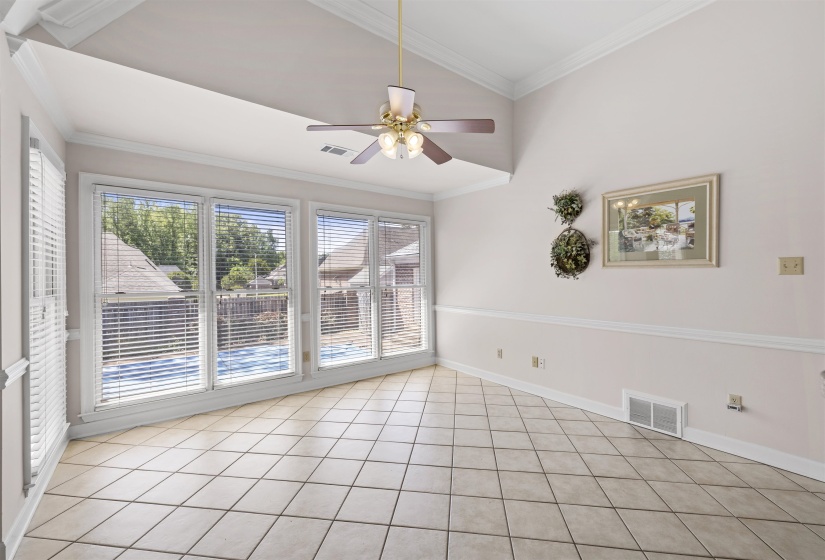 Hearth room with a ceiling fan, ornamental molding, light tile patterned floors, and vaulted ceiling