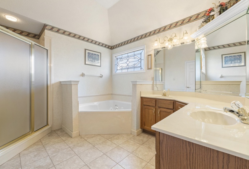 Full bathroom featuring double vanity, a bath, a shower stall, and light tile patterned floors