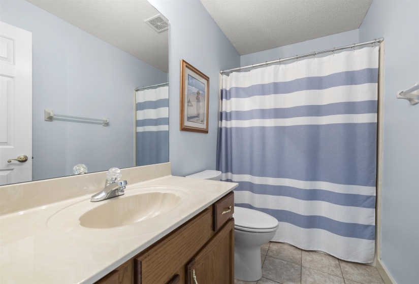 Full bath with vanity, a textured ceiling, a shower with shower curtain, and light tile patterned flooring