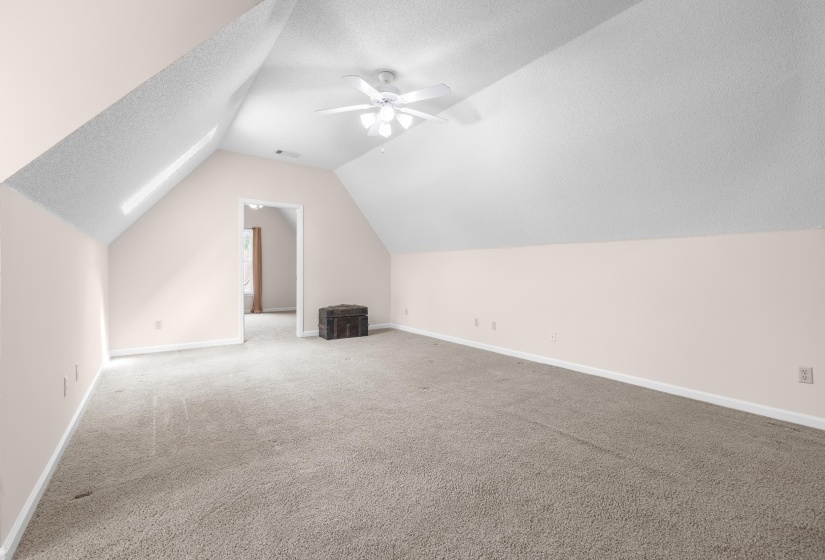 Additional living space featuring a textured ceiling, light colored carpet, and ceiling fan