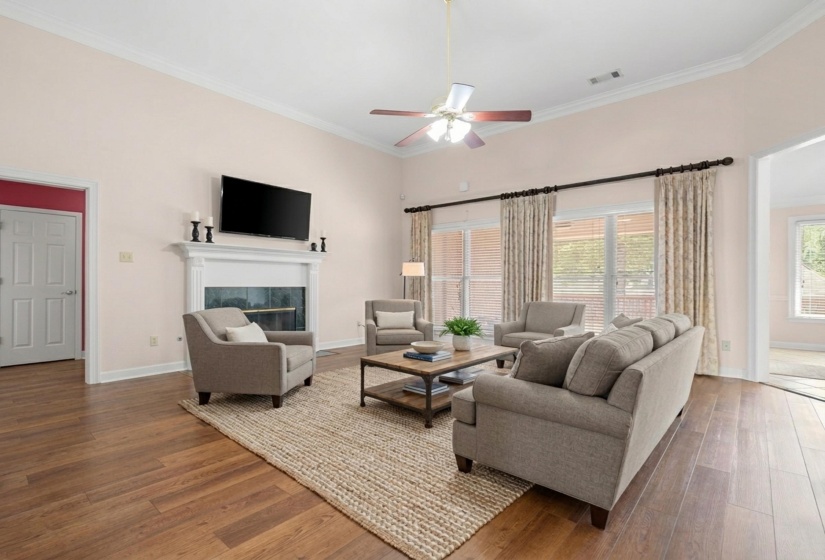 Living room featuring wood finished floors, a fireplace, a ceiling fan, and ornamental molding