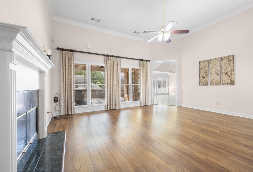 Unfurnished living room with a premium fireplace, crown molding, dark wood-style flooring, a ceiling fan, and a high ceiling