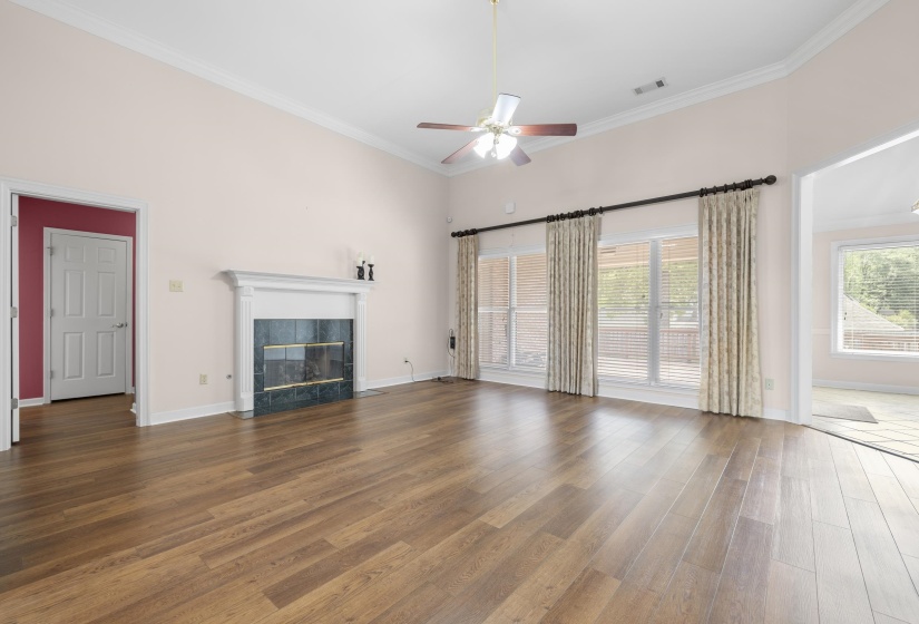 Unfurnished living room with dark wood-style floors, a ceiling fan, ornamental molding, a fireplace, and a high ceiling