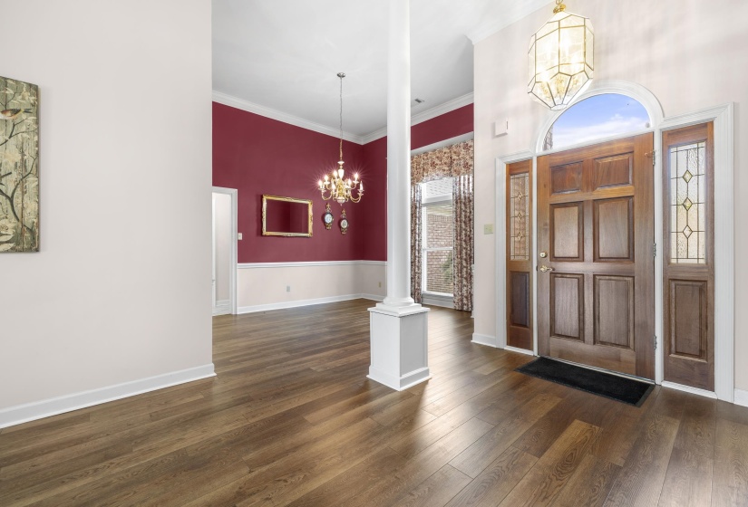 Entryway featuring a chandelier, dark wood finished floors, and crown molding