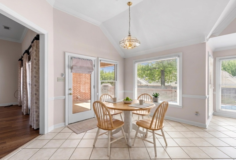 Breakfast area with lofted ceiling, crown molding, light tile patterned floors, and a chandelier