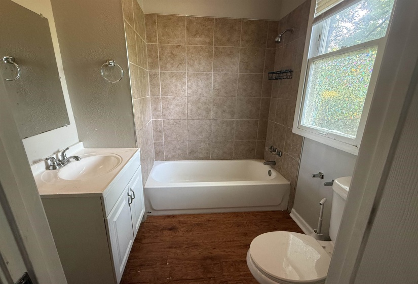 Bathroom featuring dark wood-type flooring,  shower combination, vanity, and a textured wall