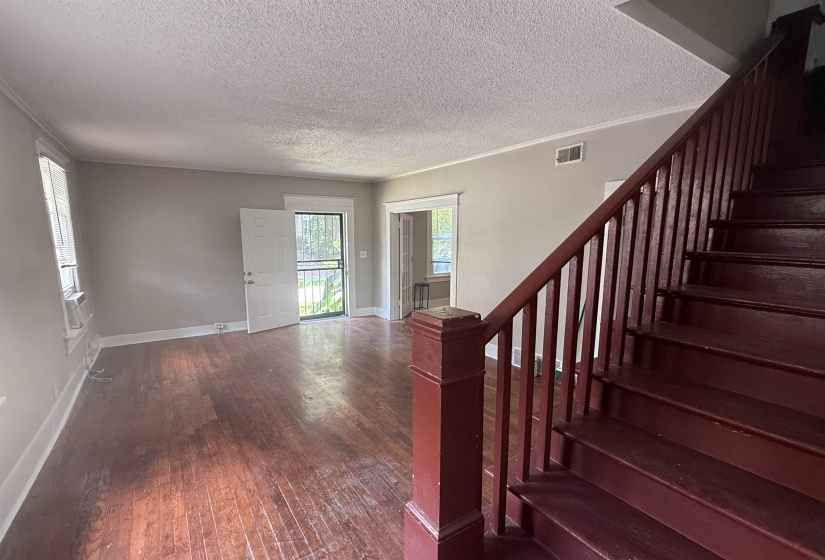 Foyer featuring dark wood-style flooring, a textured ceiling, crown molding, and stairway