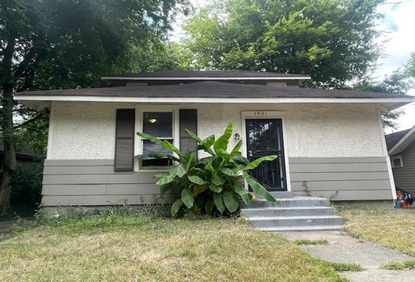 View of front of property featuring a front yard, entry steps, and stucco siding