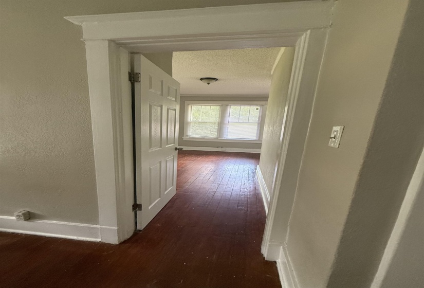 Corridor with dark wood-type flooring, a textured ceiling, and a textured wall