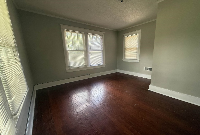 Empty room with ornamental molding, dark wood-type flooring, and a textured ceiling