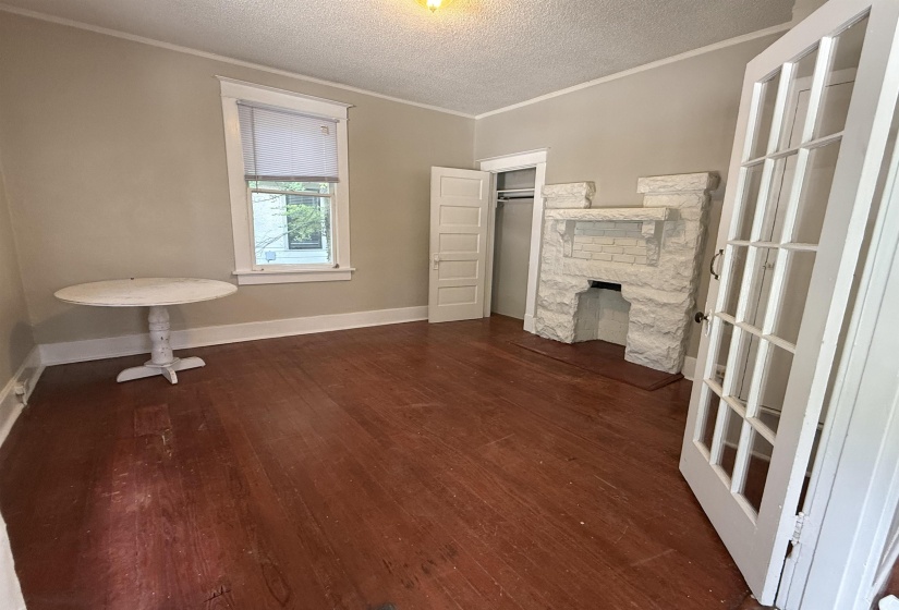 Unfurnished bedroom featuring crown molding, dark wood-type flooring, a fireplace, and a textured ceiling