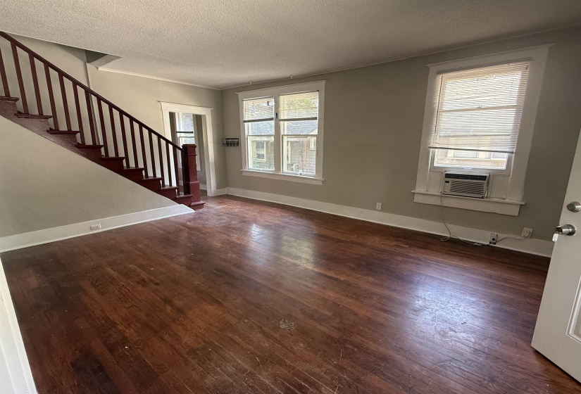 Unfurnished living room with ornamental molding, stairway, dark wood-style floors, and a textured ceiling