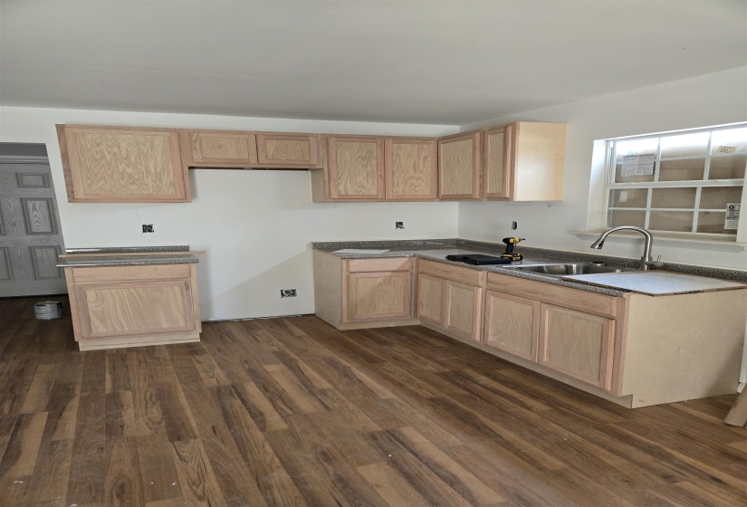 Kitchen with light wood finish cabinets and dark wood-style flooring